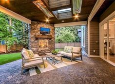 an outdoor living room with stone fireplace and seating area in front of the tv on the wall