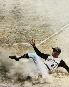 a baseball player sliding into home plate with his glove on the ground and one leg in the air