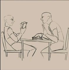 two people are sitting at a table and one is holding a book in his hand