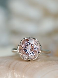 a pink diamond ring sitting on top of a piece of wood