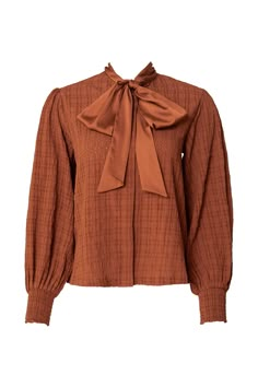 Introducing the Sybil Blouse in Brown! Made with durable brown woven fabric, this blouse features a high neckline with a functional bow for added style. The long balloon sleeve and smocked cuff add a touch of elegance, while the button up style makes it nursing friendly. The perfect addition to your wardrobe - versatile and chic! Just throw on your favorite pair of jeans and you have your new favorite fall outfit. Stylist Clothes, Blouse With Collar, Bow Tie Top, Ivy City Co, Button Up Style, Country Aesthetic, Girls Holiday Dresses, City Woman, Brown Blouse