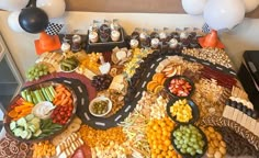 a table topped with lots of food and desserts next to white balloons in the background