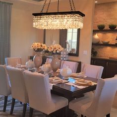 a dinning room table with white chairs and a chandelier hanging from the ceiling