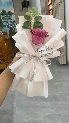 a hand holding a bouquet of flowers in it's left arm, with the ribbon wrapped around it