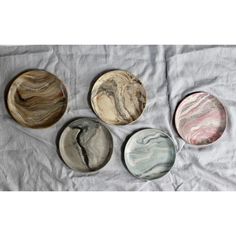 four marble plates sitting on top of a white sheet