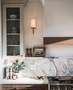 a kitchen with white marble counter tops and wooden cabinetry, along with bookshelves