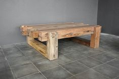 a wooden bench sitting on top of a tile floor next to a gray wall in an empty room