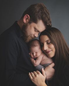 a man and woman holding a baby in their arms