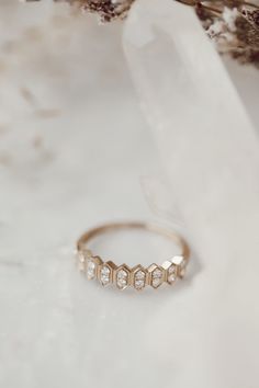 a gold ring sitting on top of a white table next to dried flowers and leaves