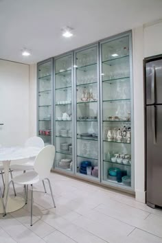 a dining room table and chairs in front of glass shelves