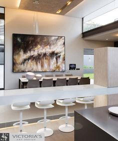 a large painting hanging in the middle of a dining room with white chairs and bar stools