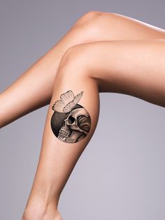 a woman's leg with a skull and flower tattoo on her left side arm