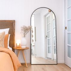 a bedroom with a large mirror on the wall next to a night stand and bed