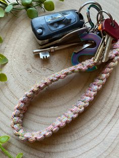 several keys are tied to a rope next to a car key chain on a tree stump