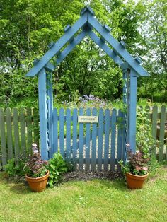 a blue garden gate with potted plants in front of it and a sign that says welcome