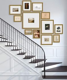 a stair case with many pictures on the wall above it and below it is a set of stairs