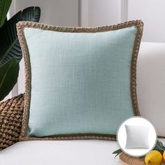 a blue pillow sitting on top of a white couch next to lemons and a plate