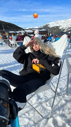 a woman sitting on top of a chair in the snow