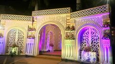 an elaborately decorated building at night with purple lights and decorations on the front door