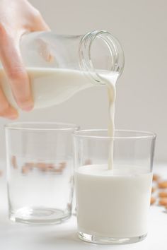 someone is pouring milk into two glasses