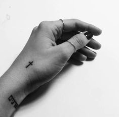 a person's hand with a cross tattoo on the middle of their left arm