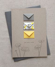 a card with an envelope and some yellow flowers on the front, sitting on a table