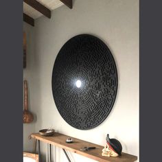 a table with a vase and some other items on it next to a large circular wall decoration