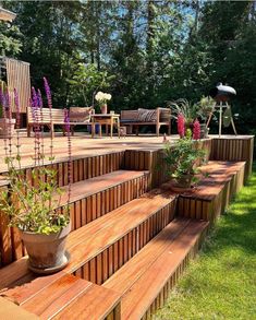 a wooden deck with planters and chairs on it in the middle of a grassy area