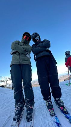 two people standing on skis in the snow with their arms around each other's shoulders