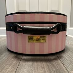 a pink and black suitcase sitting on top of a wooden floor