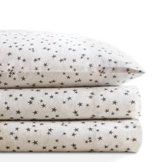 three pillows stacked on top of each other in white and black stars print, one is folded