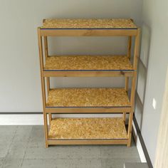 three shelving unit with wood shavings on the bottom and top shelves in an empty room