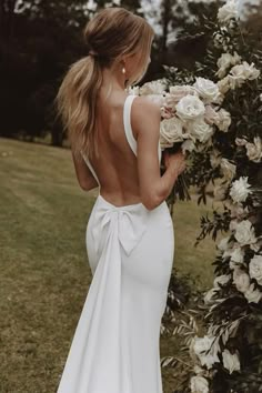 a woman in a white wedding dress holding flowers