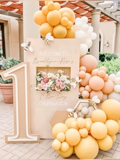 balloons and flowers are on display in front of a welcome sign for the first birthday