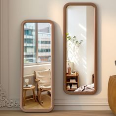 two mirrors sitting next to each other on top of a wooden floor in front of a window