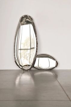 a large mirror sitting on top of a floor next to a white wall in front of a window