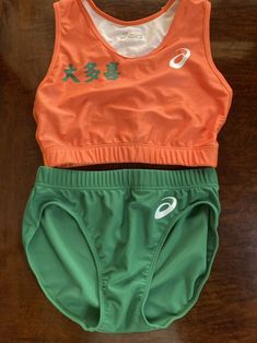 two sports bras with chinese writing on them, one in orange and the other in green