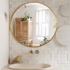 a bathroom with a sink, mirror and plants on the wall in it's corner