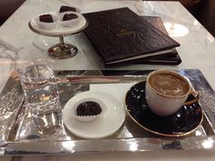 a tray with a cup of coffee and some pastries on it, along with other items