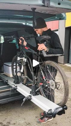 a man is loading his bike onto the back of a van with its door open