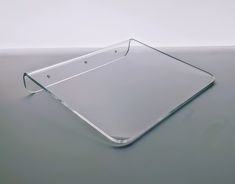 a glass tray sitting on top of a gray table next to a white wall and floor