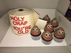 some cupcakes with googly eyes are in a box next to a roll of toilet paper