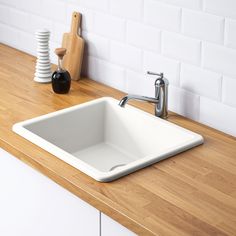 a white kitchen sink sitting on top of a wooden counter next to a cutting board