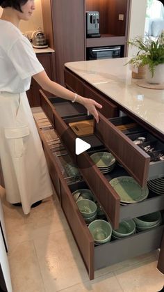 a woman standing in a kitchen next to an open drawer