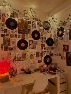 a room with many records hanging on the wall and various decorations around it, including a desk