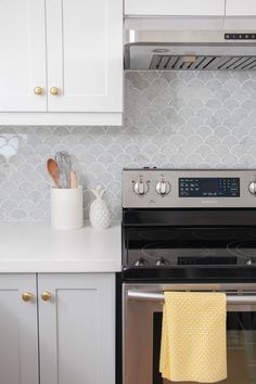 a stove top oven sitting inside of a kitchen next to white cabinets and counter tops