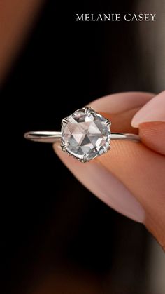 a woman's hand holding an engagement ring with a white topazte stone