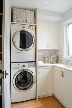 a washer and dryer are stacked in the corner of a kitchen with white cabinets