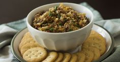 a white bowl filled with food sitting on top of a plate next to crackers