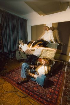 four people sitting on a rug in a room